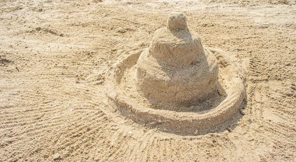 Holiday concept with sandcastle on sandy beach against a summer sky and blue sea — Photo