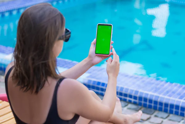 Αντίληψη: πρότυπο για μια γυναίκα εφαρμογή smartphone χρησιμοποιεί το τηλέφωνο, ενώ κάθεται δίπλα στην πισίνα Royalty Free Φωτογραφίες Αρχείου