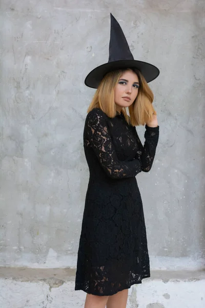 Joyeux gothique jeune femme en costume de sorcière Halloween avec chapeau sur fond gris — Photo