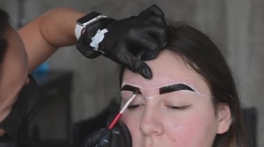Güzellik salonunun ön cephesinden ince fırça darbesi ile kaşlara boya sürüyorum.