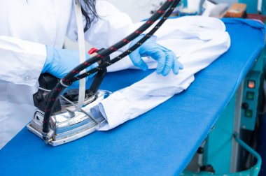 Profesyonel kuru temizlemeci müşterinin gömleğini ütülüyor. İş kadını ve küçük işletme kavramı..