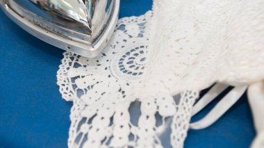 Ironing delicate wedding dress on a blue board clipart