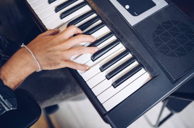 Pianist's hand on electronic piano keyboard, view from above.