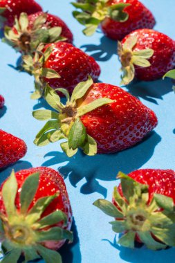 Bir deseni takip eden ve doğal ışıkla aydınlatılan birkaç çilek. Sağlıklı besinler.