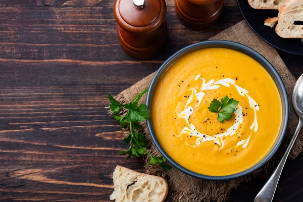 Pumpkin and carrot soup with cream and parsley Top view Copy space