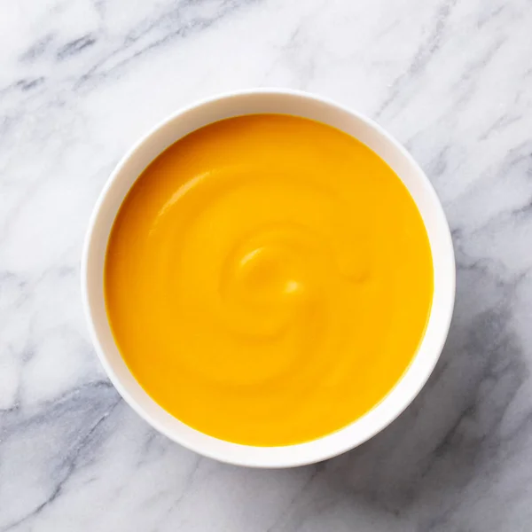 Healthy comfort pumpkin, butternut squash soup in white bowl. Marble background. Close up. Top view. — Stock Image Healthy comfort pumpkin, butternut squash soup in white bowl. Marble background. Close up. Top view. Stock Image