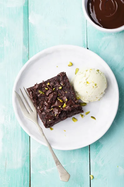 Chocolate brownie, cake, white plate on a turquoise wooden background