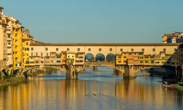 İtalya, Floransa 'da güneşli güzel bir sabahta Arno Nehri' nde kürek çeken kürekçiler. Arka planda tarihi Ponte Vecchio var.