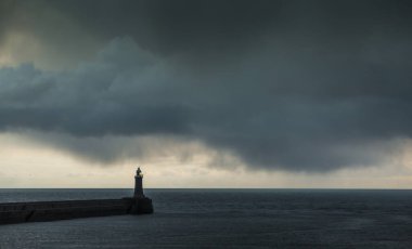 Şafak vakti Tyne Nehri 'nden Kuzey Denizi' ne bakarken büyük gri yağmur bulutları rıhtımda beliriyor.