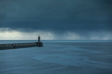 Şafak vakti Tyne Nehri 'nden Kuzey Denizi' ne bakarken büyük gri yağmur bulutları rıhtımda beliriyor.