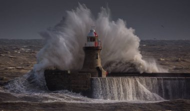 Giant waves batter the 15metre tall lighthouse which guards the south pier at the mouth of the Tyne at South Shields, England clipart
