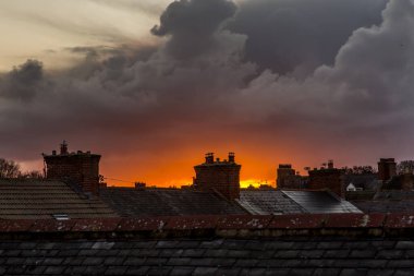 Buz kaplı çatı kiremitleri ve bacalar ve bir şehir sahnesinde gün doğumu