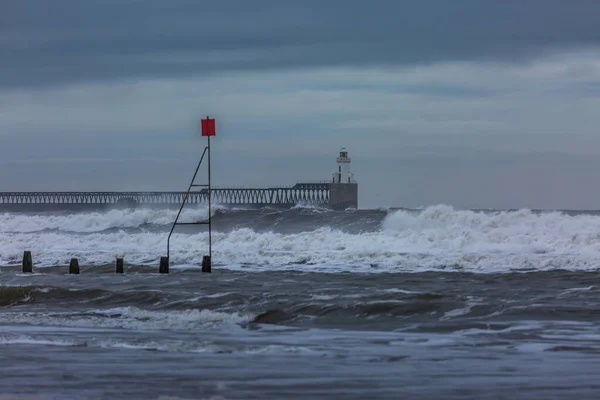 Northumberland 'daki Blyth sahilinde fırtınalı ve kasvetli bir gün, dalgalar kıyıları vururken