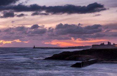 Sunrise at a chilly Cullercoats Bay in the north east of England, with Tynemouth Pier and the lighthouse in the distance. clipart
