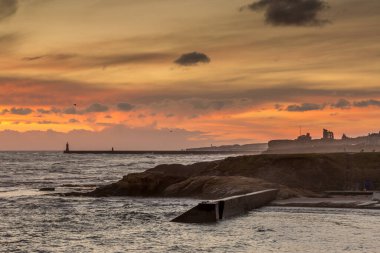 İngiltere 'nin kuzeydoğusunda serin bir Cullercoats Körfezi' nde gün doğumu, uzakta Tynemouth İskelesi ve deniz feneri.