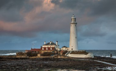 Büyük Bulutlar Whitley Körfezi 'ndeki St. Mary Deniz Feneri' nin üzerinde asılı gelgitle birlikte gelgit geçidi görünüyor.