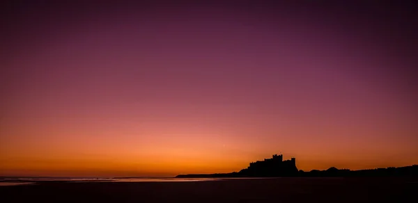 Den Ikoniska Bamburgh Castle Vid Soluppgången Med Den Närliggande Stranden — Stockfoto