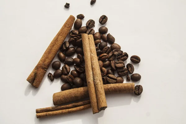 Granos de café tostado y palitos de canela sobre fondo blanco — Foto de Stock