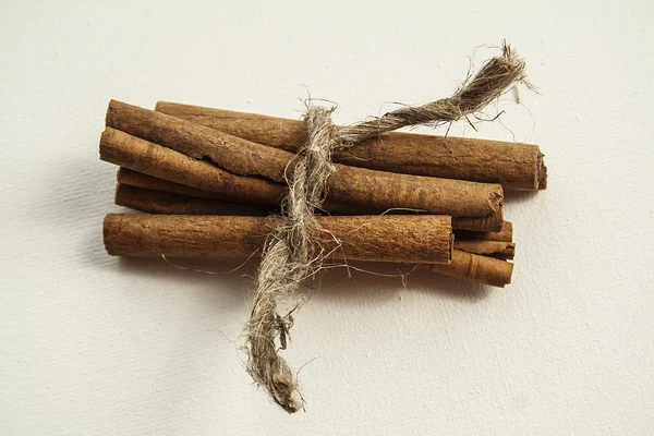 Palos de canela atados con una cuerda sobre un fondo blanco — Foto de Stock