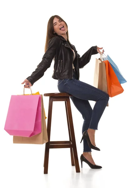 Dívka s nákupy sedí a ukazuje svůj jazyk. — Stock fotografie