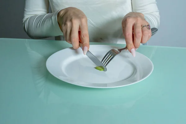 Mulher com anorexia corta uma pequena porção de comida. — Fotografia de Stock