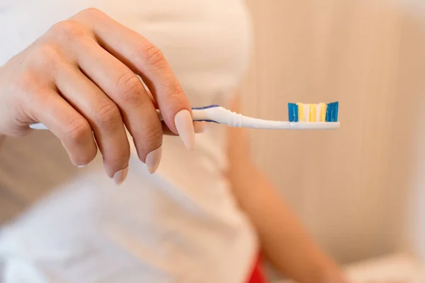 Γυναίκα κρατώντας μια οδοντόβουρτσα στο χέρι της στην μπανιέρα. — Φωτογραφία Αρχείου