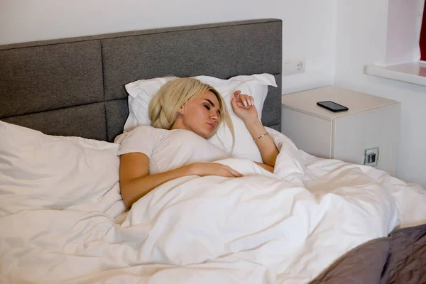 Girl sleeps in a large bed at home under blanket.