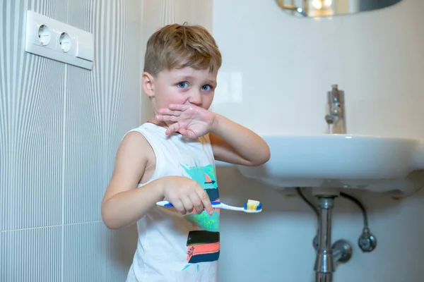 Niño cepillarse los dientes con un cepillo de dientes en el baño. — Foto de Stock