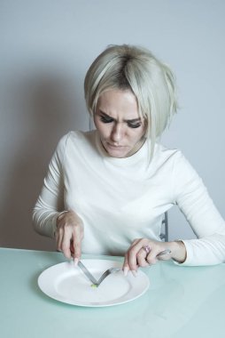 İştahsız hasta kız mutfak masasında oturuyor..