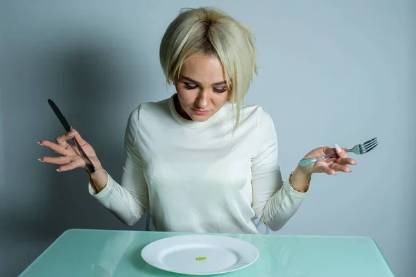 Ziek meisje met anorexia zit aan de tafel. — Stockfoto