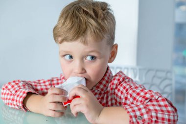 Çocuk masaya oturur ve çikolata yer..