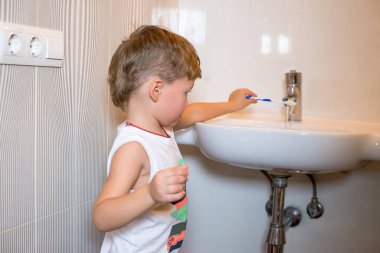 Diş fırçası olan küçük bir çocuk dişlerini fırçalıyor..