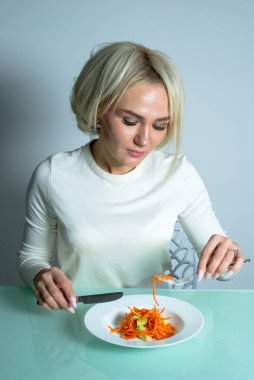 Girl eats a healthy and tasty salad in kitchen.