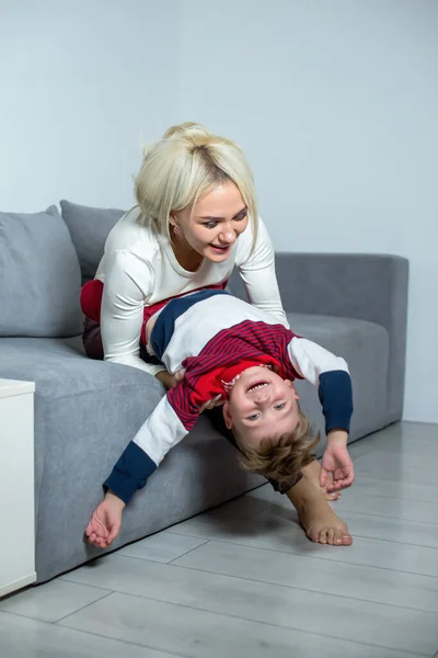 Moeder speelt met kleine zoon thuis op het bed. — Stockfoto