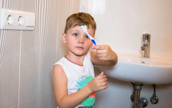Chlapec se zubním kartáčkem stojí v koupelně. Royalty Free Stock Fotografie