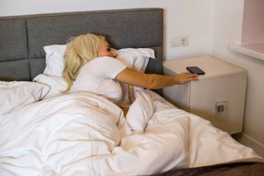 Yataktaki kız telefondaki alarmı kapatıyor..