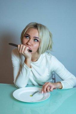 Anoreksik kız masaya oturur ve yemek yer..