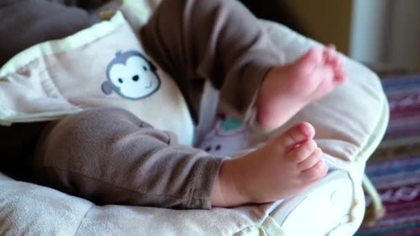 Cute feet of a newborn baby. The child lies in the childs vibrating chair — Stock Video
