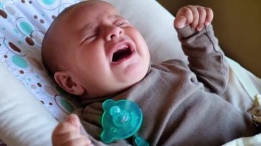 Yeni doğmuş bebek yakından ağlıyor. Annem onu meme ucuyla sakinleştirmeye çalışıyor.