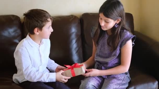 Flickan gratulerar pojken med en gåva. Barn firar Alla hjärtans dag — Stockvideo
