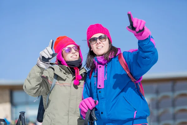 Två kvinnor skidåkare pekar — Stockfoto