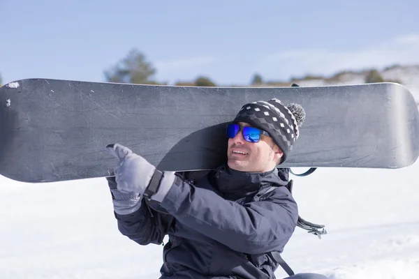 Homem feliz com snowboard mostrando algo com a mão — Fotografia de Stock