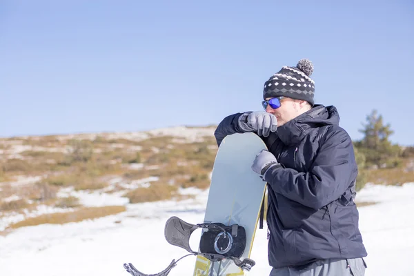 Mannen i solglasögon med snowboard tittar bort — Stockfoto