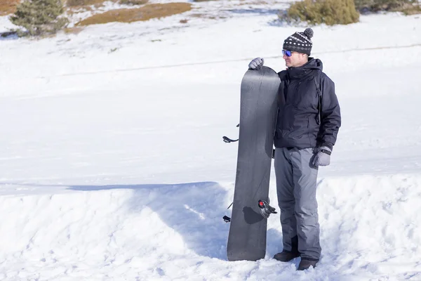 Человек с сноубордом смотрит в сторону — стоковое фото