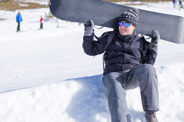 Портрет улыбающегося человека с сноубордом, смотрящего в сторону — стоковое фото
