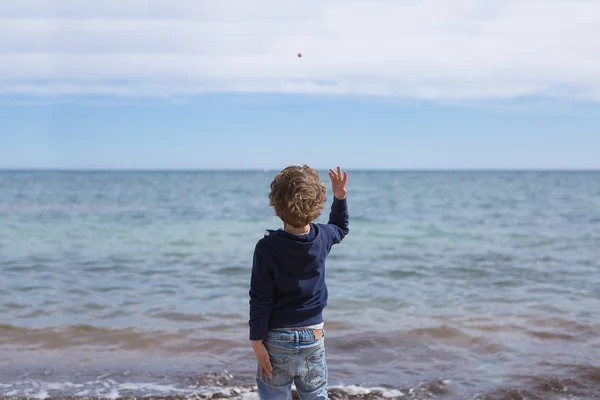 Back view of boy throwig stone in water — Stock Photo, Image