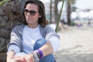 Gülümseyen kadın Palm gövdede yaslanmış