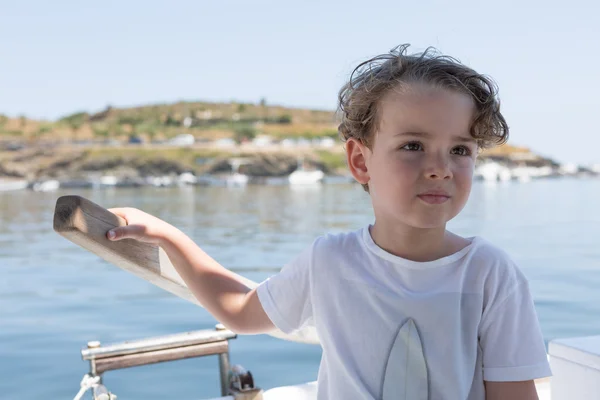 Mooie jongen met golvende haren op boot — Stockfoto