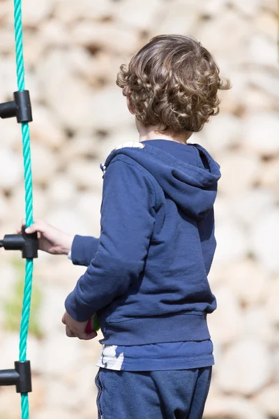 Jongen met krullend haar op speelplaats — Stockfoto