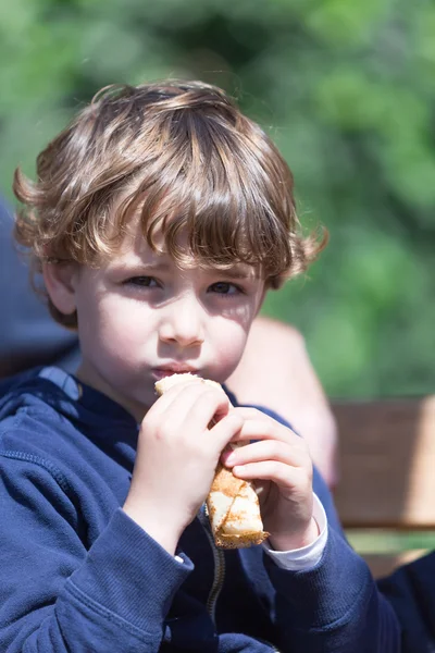 Bonito pouco menino comer panqueca ao ar livre — Fotografia de Stock